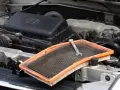 Wymiana filtrów w samochodzie. Klucz leży na zużytym filtrze powietrza, gotowym do wymiany w komorze silnika.