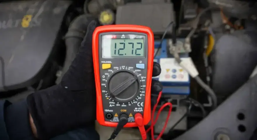 Multimetr pokazuje 12.72V, co może oznaczać, że akumulator nie trzyma napięcia. Sprawdzanie stanu baterii w samochodzie.