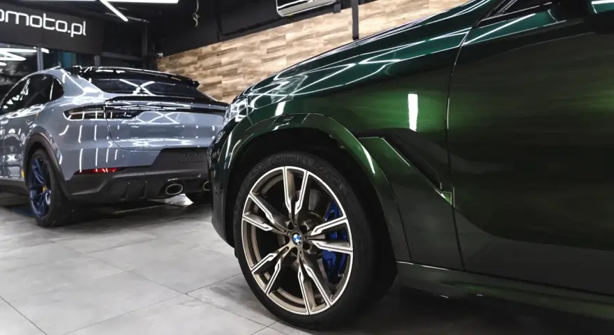 Lśniące, zielone BMW i szare Porsche w garażu. To efekt profesjonalnego auto detailingu, który przywraca blask lakierowi i dba o każdy detal pojazdu.