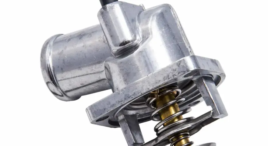 Metalowy termostat w samochodzie z widoczną sprężyną i zaworem. Kluczowy element układu chłodzenia.