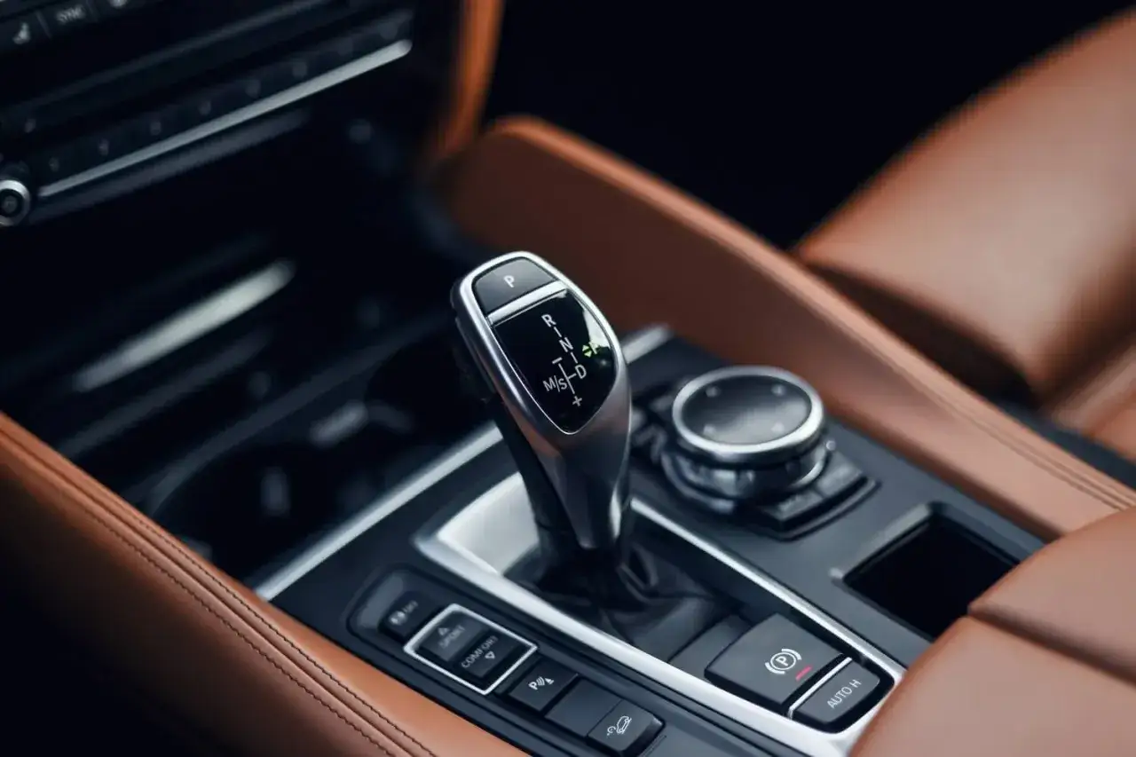 Dźwignia zmiany bieg&oacute;w ZF 8HP w luksusowym wnętrzu samochodu z brązową sk&oacute;rzaną tapicerką.