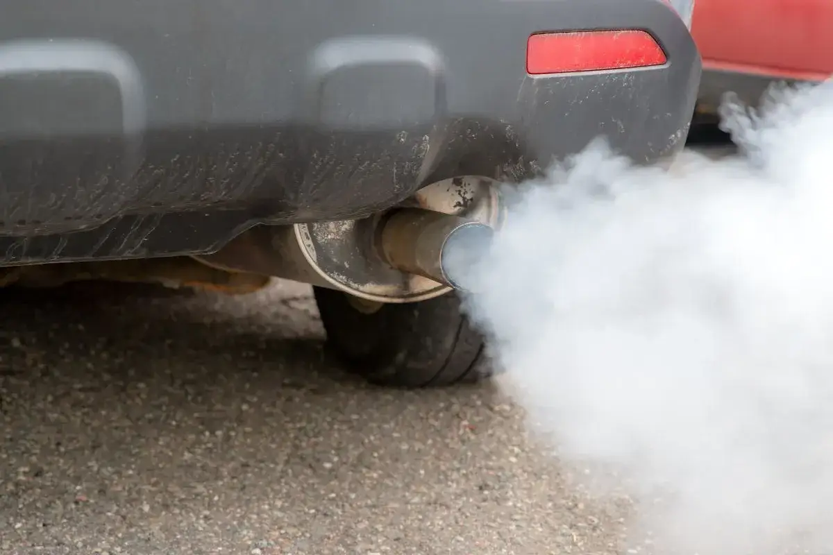 Z rury wydechowej samochodu wydobywa się biały dym. Diesel kopci na biało, sygnalizując problem.
