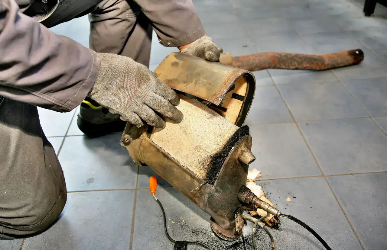 Mechanik ogląda uszkodzony filtr cząstek stałych, kt&oacute;ry wymaga wymiany.